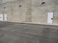 a small white door is next to a concrete wall with two light bulbs on it