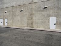 a small white door is next to a concrete wall with two light bulbs on it