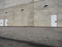 a small white door is next to a concrete wall with two light bulbs on it