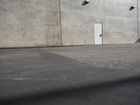 a small white door is next to a concrete wall with two light bulbs on it