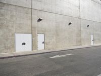 a small white door is next to a concrete wall with two light bulbs on it