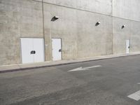 a small white door is next to a concrete wall with two light bulbs on it