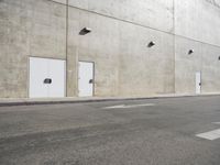 a small white door is next to a concrete wall with two light bulbs on it