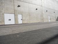 a small white door is next to a concrete wall with two light bulbs on it