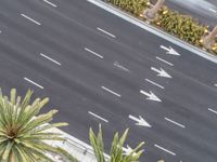 an aerial view looking down at the street where two cars are parked and some are white arrows on a black asphalt road