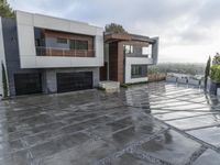 this modern residence has a stone driveway in front of the house and landscaping on the side