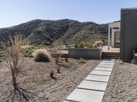 this home is built in the desert with no grass on the lawn, and has stairs leading into a garden area and yard