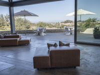 a big living room with brown furniture and lots of windows overlooking the scenery and desert