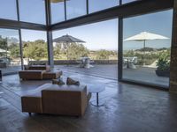 a big living room with brown furniture and lots of windows overlooking the scenery and desert