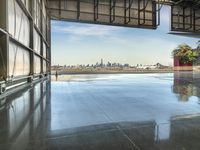 the view of a city from a warehouse with an open door, viewed from inside