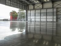 a wet floor in an empty building with red and white walls behind it and several trees