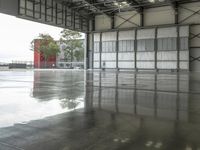 a wet floor in an empty building with red and white walls behind it and several trees