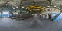 a fish - eye lens image of a large warehouse with stairs and tables and a second in the front