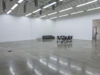 a room with chairs and tables in it and one black couch inside the white wall