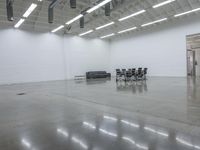 a room with chairs and tables in it and one black couch inside the white wall