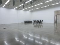 a room with chairs and tables in it and one black couch inside the white wall