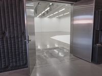 open door that leads to the inside of a commercial space with grey walls and white flooring