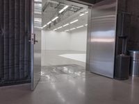 open door that leads to the inside of a commercial space with grey walls and white flooring