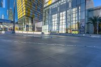 an empty area with empty road and building in background with blue sky above it and glass skyscrapers behind