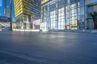 an empty area with empty road and building in background with blue sky above it and glass skyscrapers behind