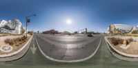 an upside down panorama showing a street and the sun behind it with buildings in the background