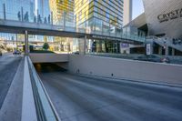 a concrete walkway leading to an underpass in front of high rise skyscrapers and stairs