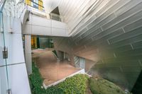 a view of the entrance to an outside building from another room below a glass and steel staircase