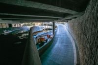 some trucks are parked underneath an overpass near buildings and water features in the streets