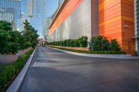 a wide road is surrounded by orange walls and tall skyscrapers near the water front