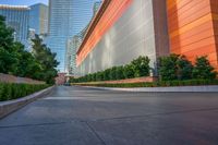 a wide road is surrounded by orange walls and tall skyscrapers near the water front