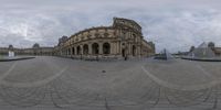 a fish eye lens photo of the louvrer at paris with the statue in the background