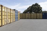 a group of multiple containers with trees behind them in a parking lot next to the road