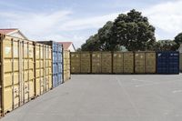 a group of multiple containers with trees behind them in a parking lot next to the road