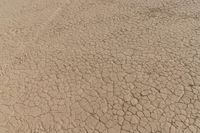 an airplane is flying low over some dry ground in the desert, with blue clouds overhead