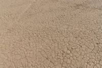 an airplane is flying low over some dry ground in the desert, with blue clouds overhead