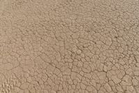 an airplane is flying low over some dry ground in the desert, with blue clouds overhead