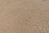 an airplane is flying low over some dry ground in the desert, with blue clouds overhead