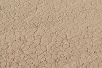 an airplane is flying low over some dry ground in the desert, with blue clouds overhead