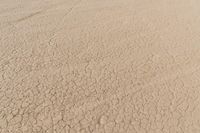 an airplane is flying low over some dry ground in the desert, with blue clouds overhead