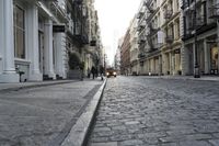 a paved cobblestone street and brick buildings in the city with people walking on the sidewalk