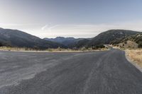 an empty mountain road with rocks and grass near it and two motorcycles parked in front of the road