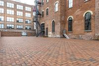 red brick floor with two building in the background from top of a roof and on the ground is a brick wall