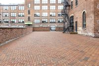 red brick floor with two building in the background from top of a roof and on the ground is a brick wall