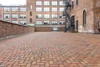 red brick floor with two building in the background from top of a roof and on the ground is a brick wall