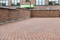 red brick floor with two building in the background from top of a roof and on the ground is a brick wall
