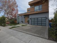 two garages are adjacent each other on the sidewalk near a house with a tree