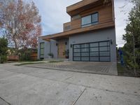 two garages are adjacent each other on the sidewalk near a house with a tree