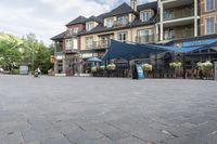 the front view of some very pretty restaurants on a street corner in canada, with blue umbrellas over tables