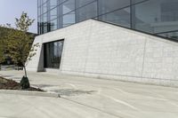 a white building has concrete walls and an empty parking lot with a small fire hydrant