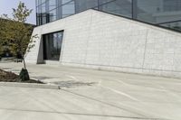 a white building has concrete walls and an empty parking lot with a small fire hydrant